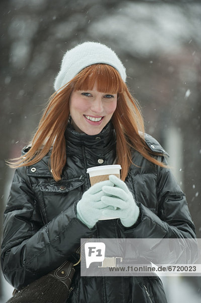 Woman holding coffee in snow