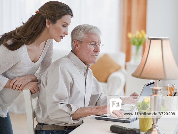 Daughter helping senior father with computer
