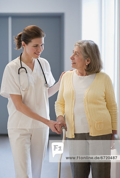 Nurse helping senior woman with cane