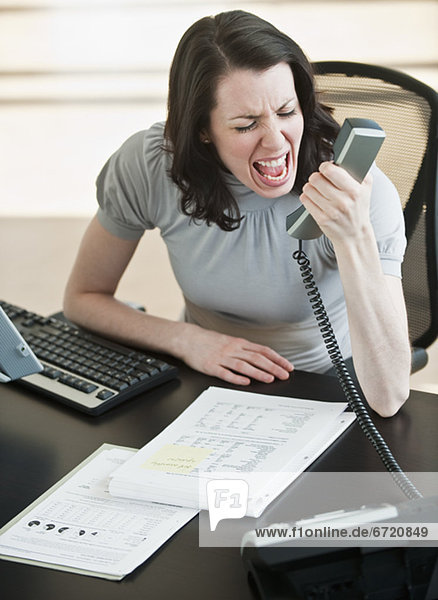 Stressed business woman using telephone in office