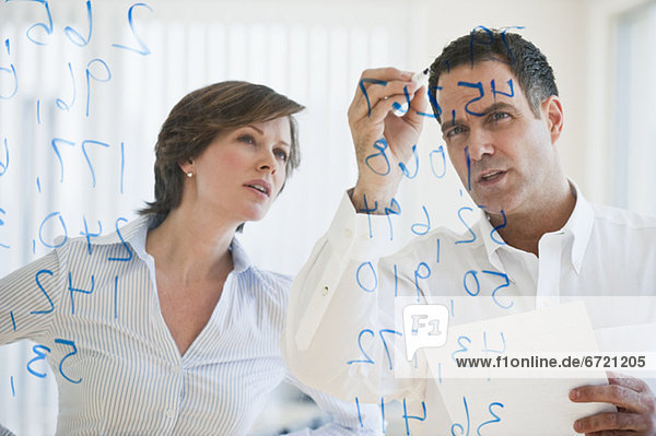 Mature businesswoman and businessman making calculations