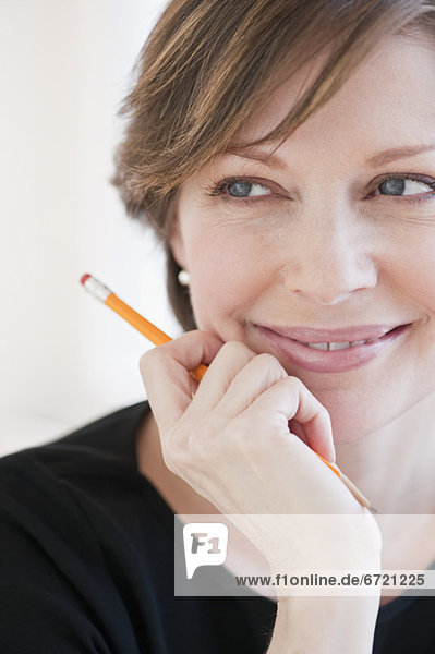 Successful mature businesswoman holding pencil and smiling