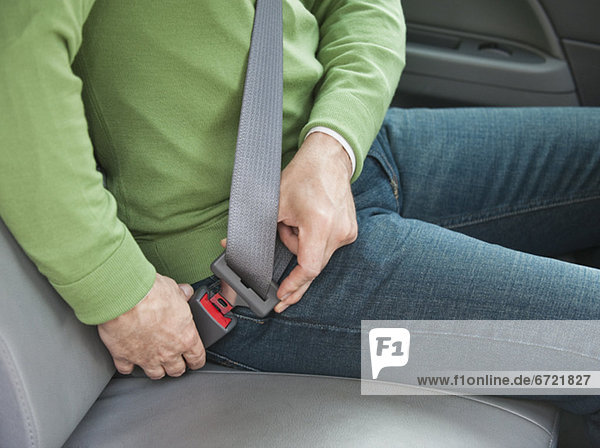 Man buckling seat belt in car
