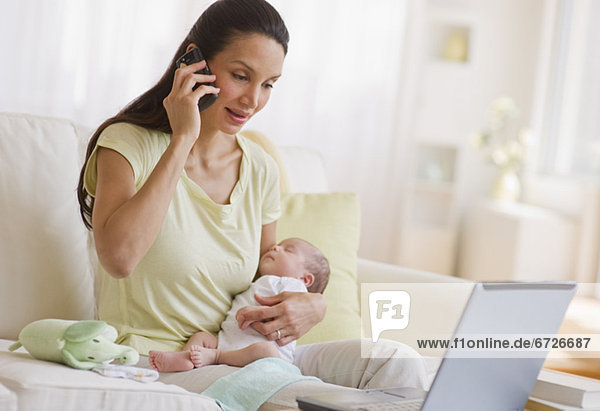 Mother talking on phone while holding her baby