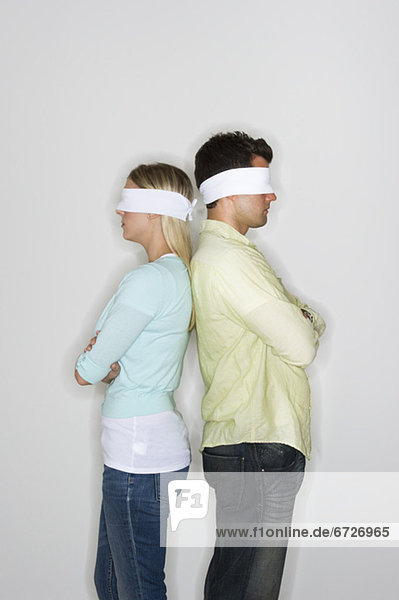 Blindfolded couple standing back to back