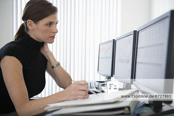 Woman in office working at desk with computers