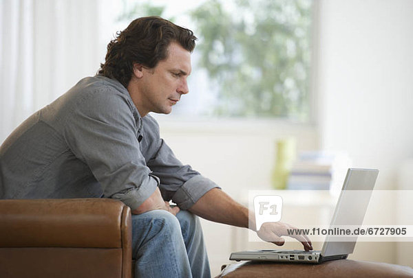 Man on armchair using laptop