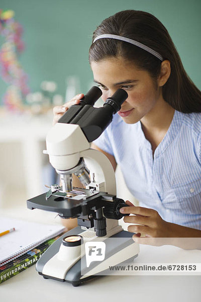 Schoolgirl (12-13) using microscope