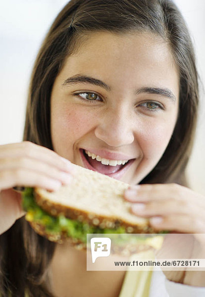 Girl (12-13) eating sandwich