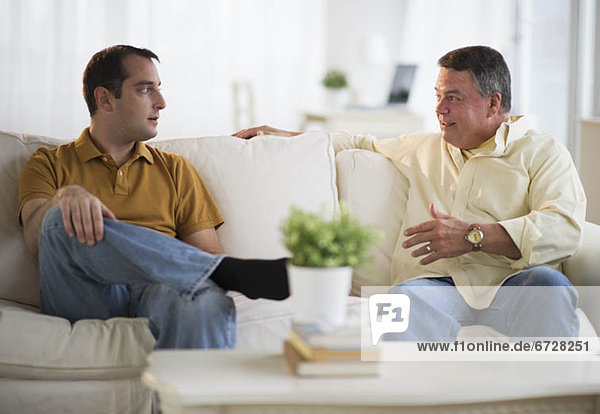 USA  New Jersey  Jersey City  Father and son talking on sofa in living room