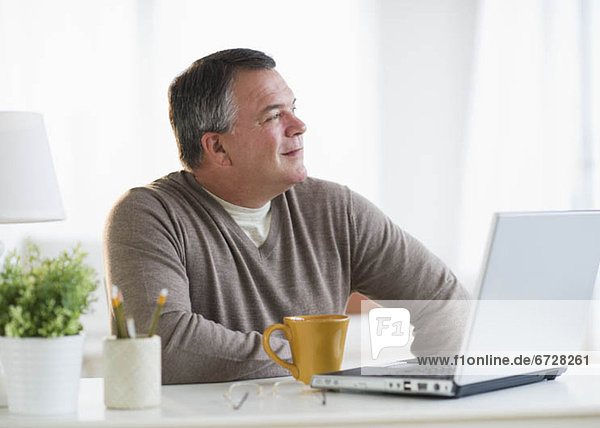 USA  New Jersey  Jersey City  Pensive man using laptop in living room