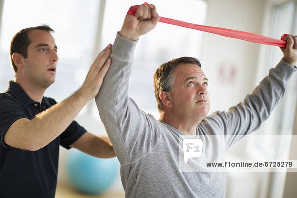 USA  New Jersey  Jersey City  Fitness instructor assisting man in gym