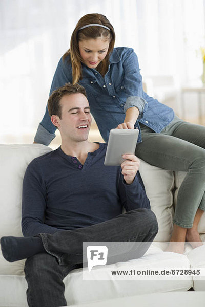 USA  New Jersey  Jersey City  Portrait of young couple sitting on sofa with digital tablet