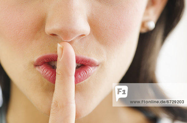 Junge Frau mit Finger auf den Lippen  Nahaufnahme mund