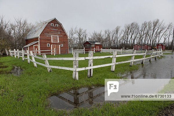 'A Barn And White Fence Surrounded By Pools Of Water From Flooding