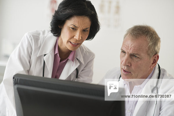 Pair of mature doctors discussing in front of computer