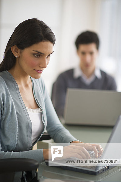 Business man and woman using laptops in office