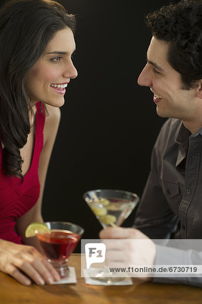 Young couple having drinks and flirting  studio shot