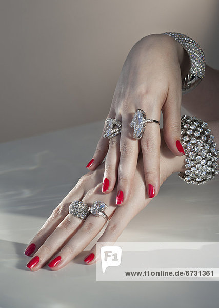 Close up of woman's hands with red nail polish and diamond jewelry