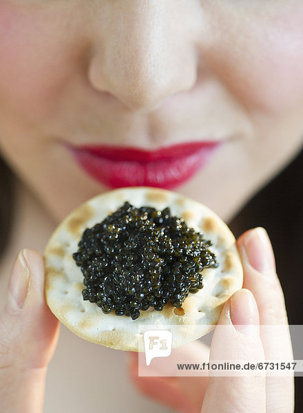 Young woman eating caviar snack  close-up of lips