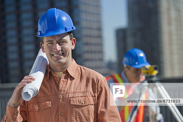 USA  New Jersey  Jersey City  portrait of construction worker holding rolled up blueprint