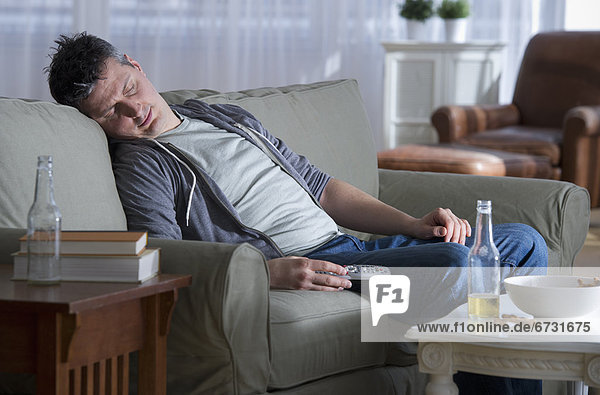 USA  New Jersey  Jersey City  man sitting on sofa  holding remote control and sleeping