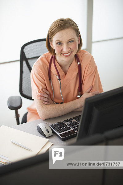 USA  New Jersey  Jersey City  female nurse sitting at desk and smiling