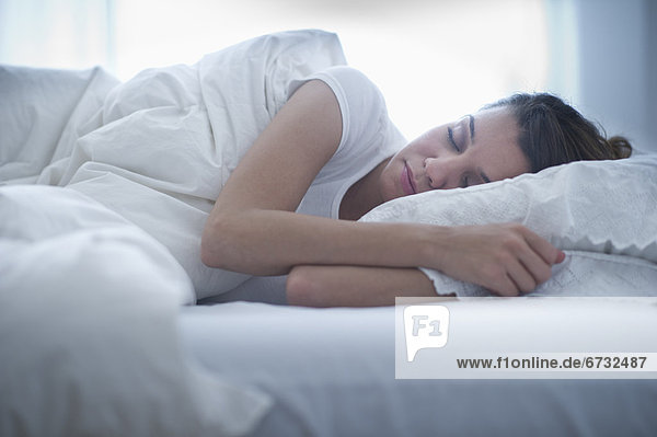Happy young woman sleeping in bed