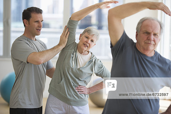 Man assisting senior people exercising