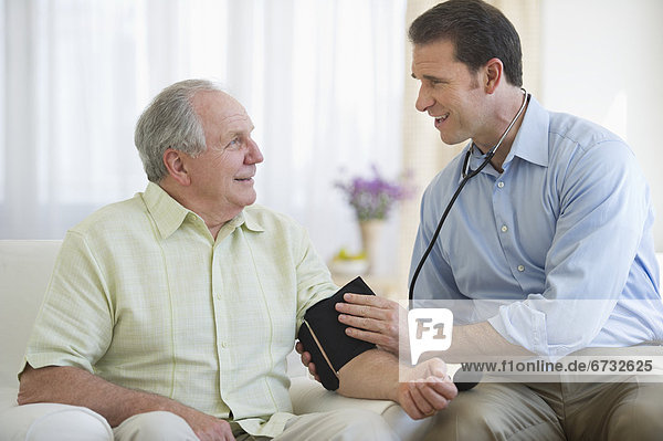 Smiling man taking senior man's blood pressure