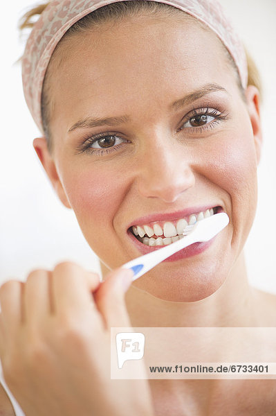 Studio portrait of woman brushing teeth
