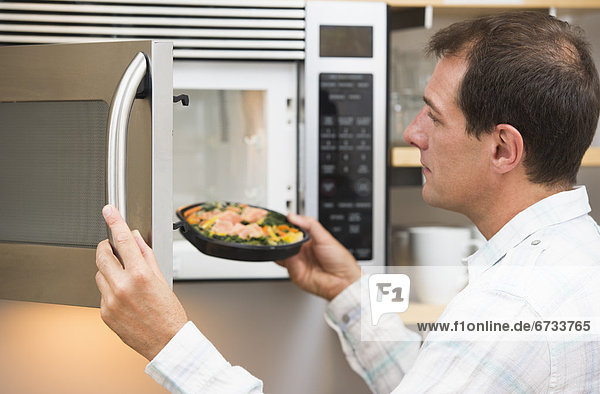 Man inserting meal in microwave oven