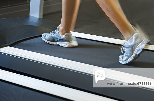 Low section of woman walking on treadmill