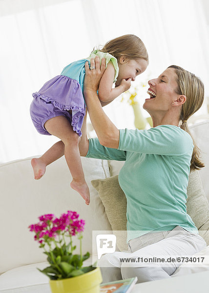 Mother playing with daughter (2-3) on sofa