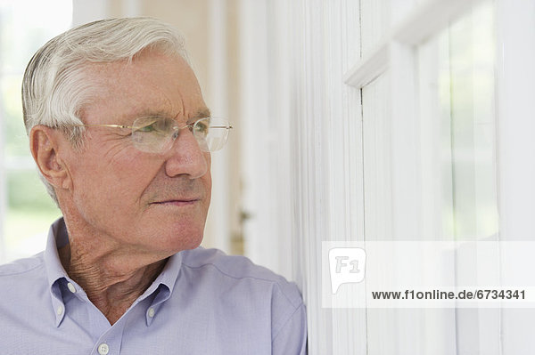 Portrait of senior man looking through window
