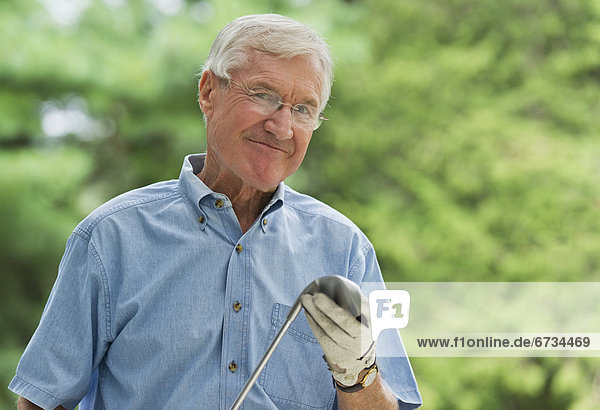 älterer Mann hält Golfclub  portrait