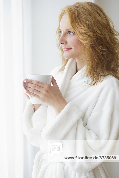 Woman in bathrobe drinking coffee