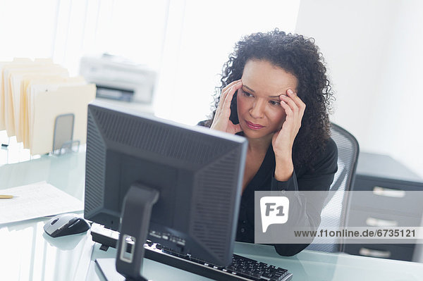 Business woman using computer holding head in hands