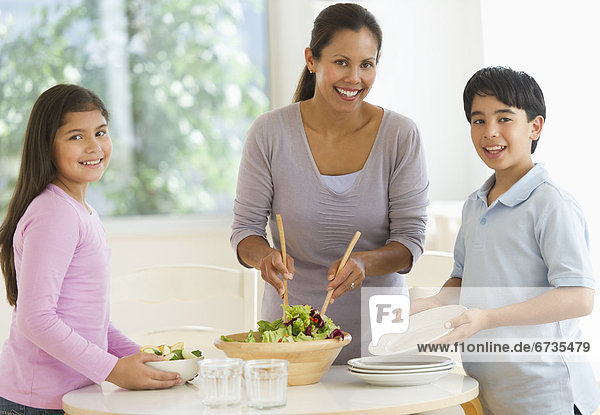 Mother with son (12-13) and daughter (10-11) preparing salad
