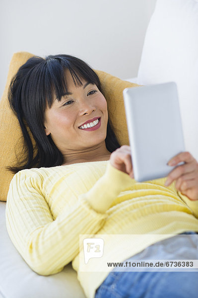 liegend liegen liegt liegendes liegender liegende daliegen benutzen Frau Couch lächeln Tablet PC