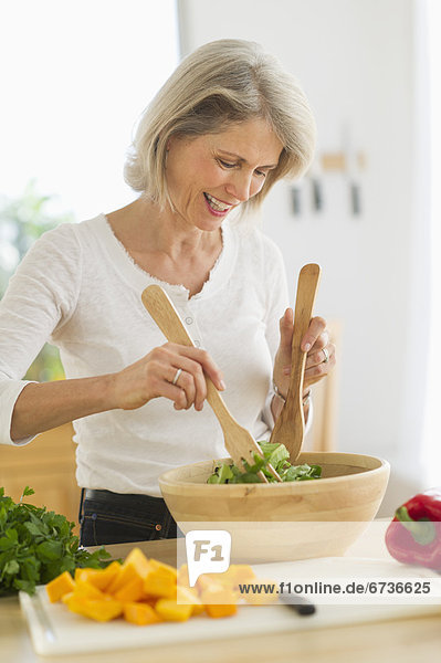 Portrait of senior woman preparing salad in kitchen