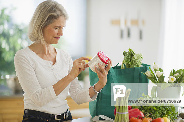 Portrait of senior woman checking product in kitchen