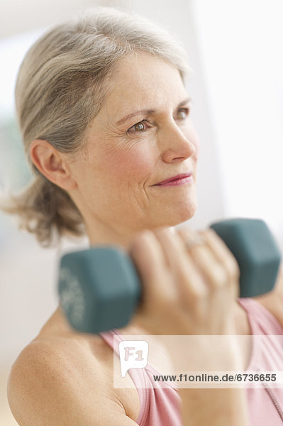 Portrait of senior woman exercising with dumbbells in gym