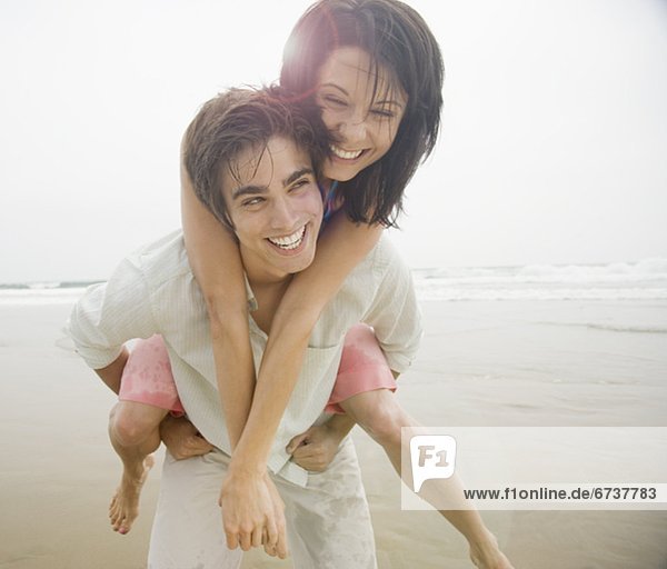 Mann mit Frau piggyback ritt am Strand