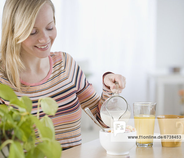 Woman pouring milk into cereal