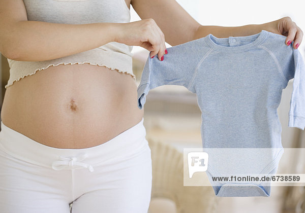 Pregnant Frau hält Baby-Kleidung
