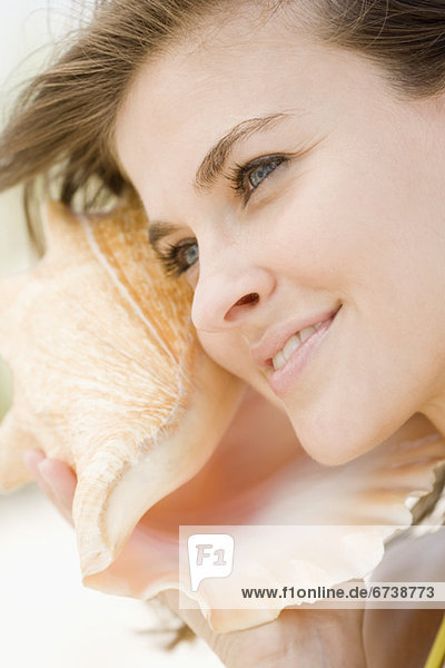 Woman listening to conch shell