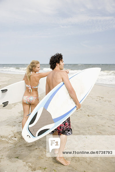 Couple holding surfboards at beach