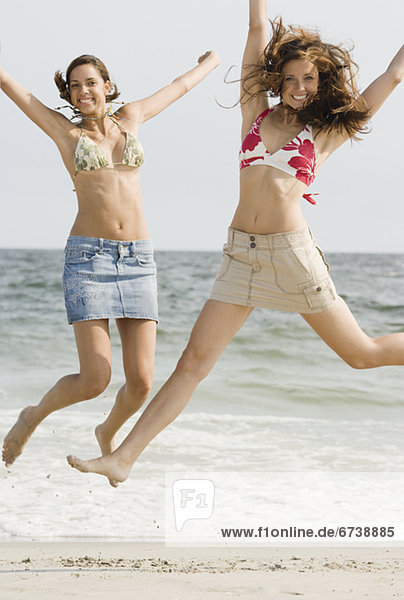 Junge Frauen am Strand springen