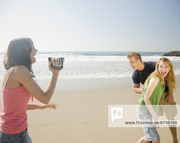 Woman video recording friends at beach